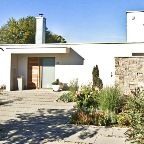 Modernes Haus mit klaren Linien, Garten und klaren Gehwegen.